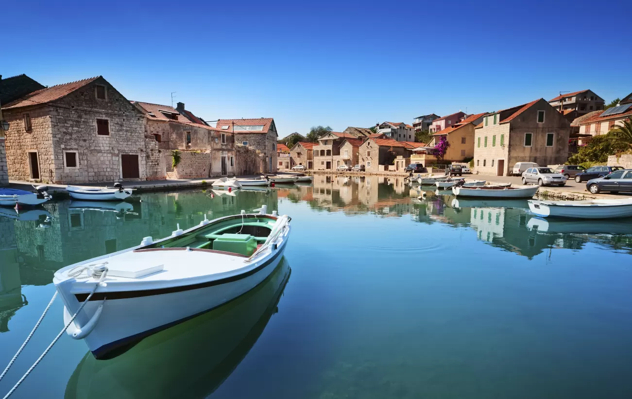 A boat sits in the still water outside a small eastern European town.