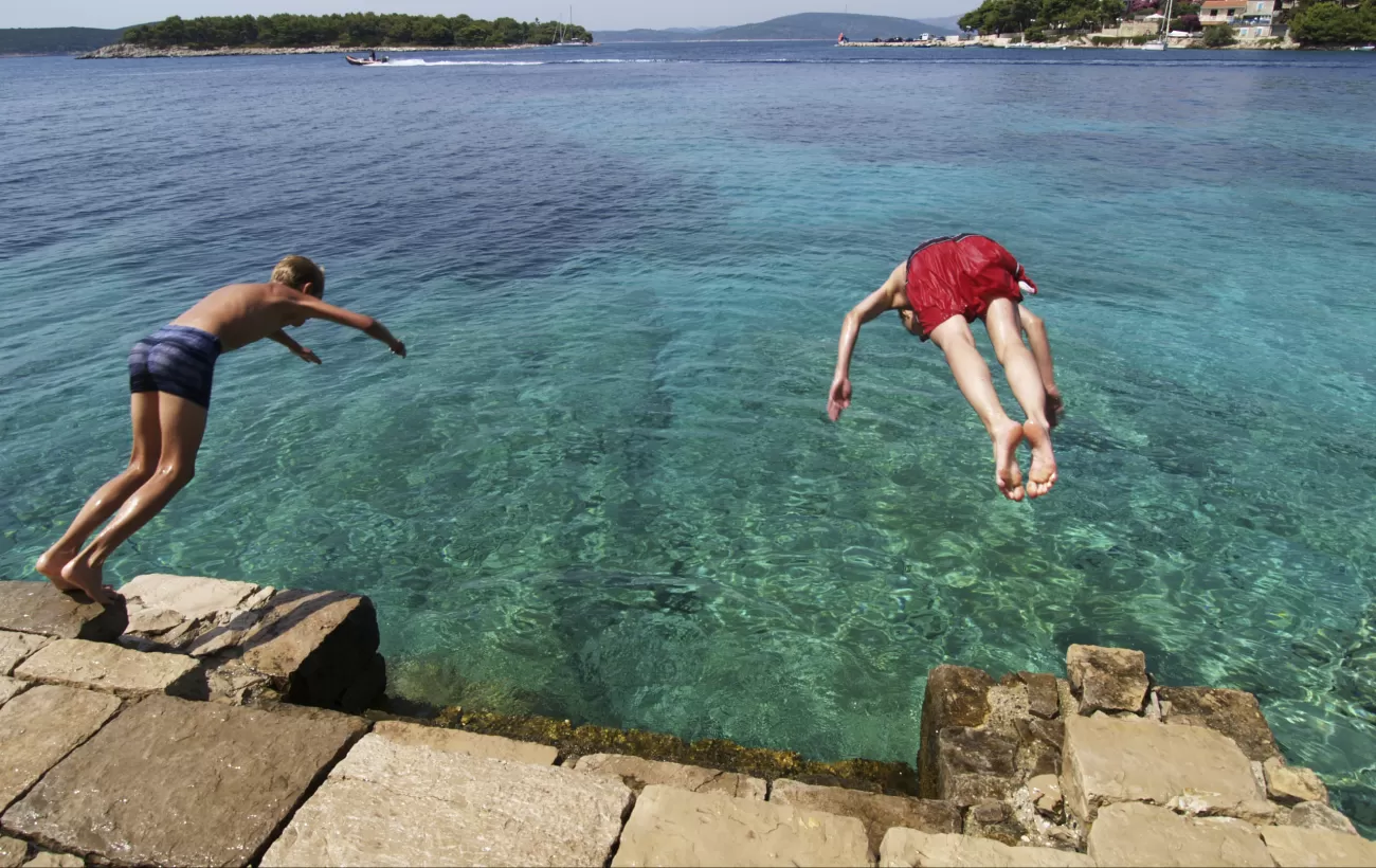 Two boys take a dive off the rocks.