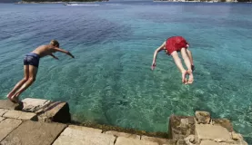 Two boys take a dive off the rocks.