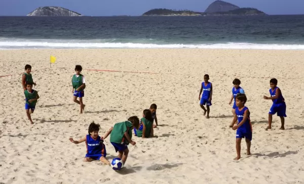 Young children playing soccer on the beach in Brazil