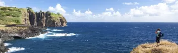 A hiker overlooks the cliffs on the ocean.