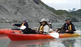 Travelers kayak through the cold Alaska waters