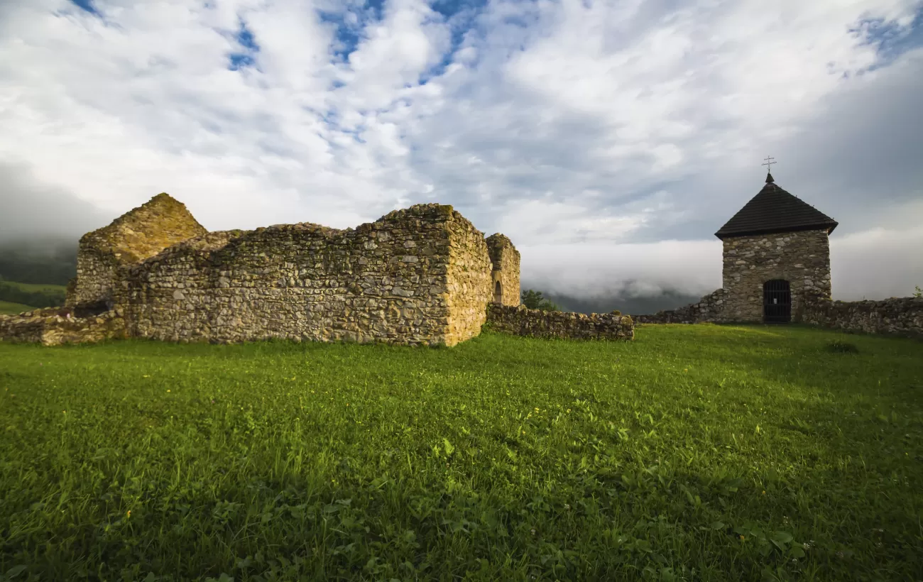 A building ruin amongst a green Slovakia landscape.