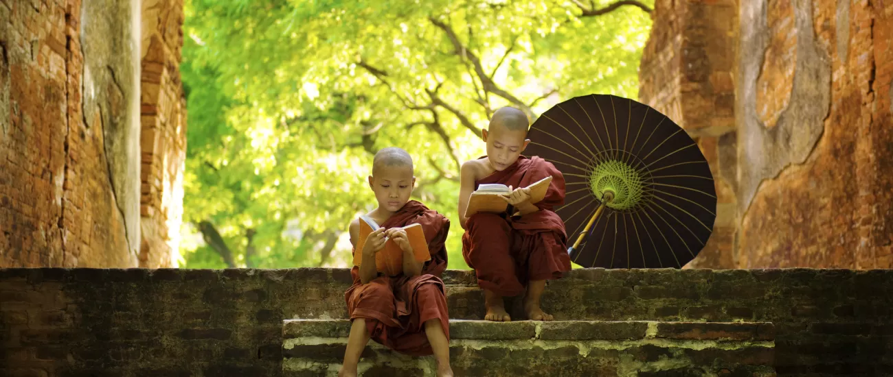 Two young monks read on the steps of a temple