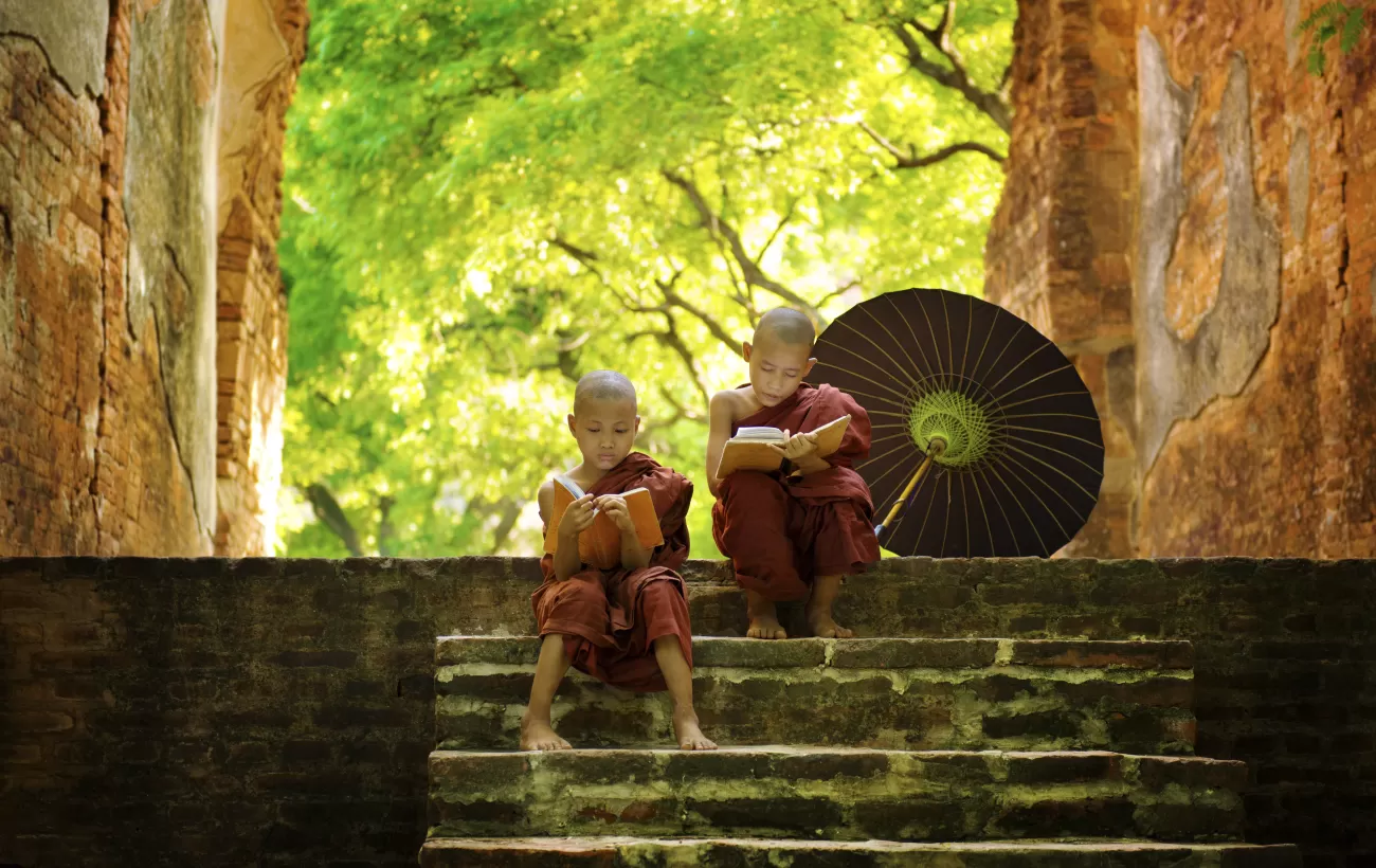 Two young monks read on the steps of a temple