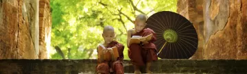 Two young monks read on the steps of a temple