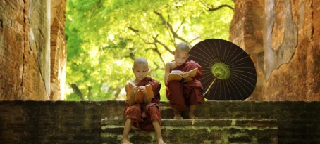 Two young monks read on the steps of a temple