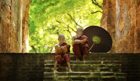 Two young monks read on the steps of a temple