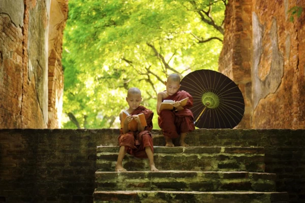 Two young monks read on the steps of a temple