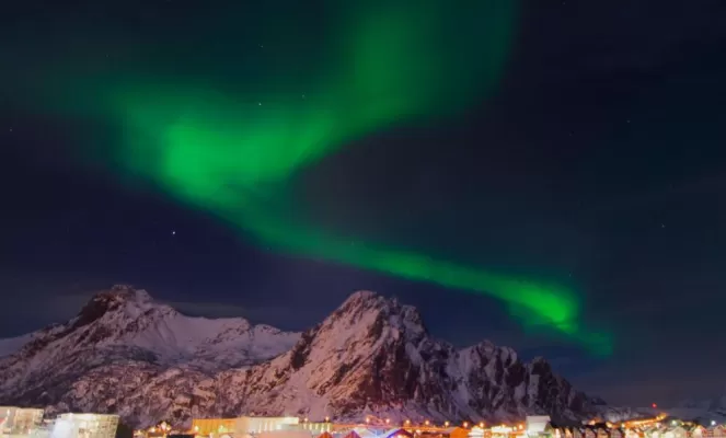 The mystical northern lights dance over a small Norwegian town