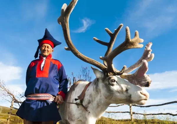 A local man in traditional norwegian dress and his reindeer