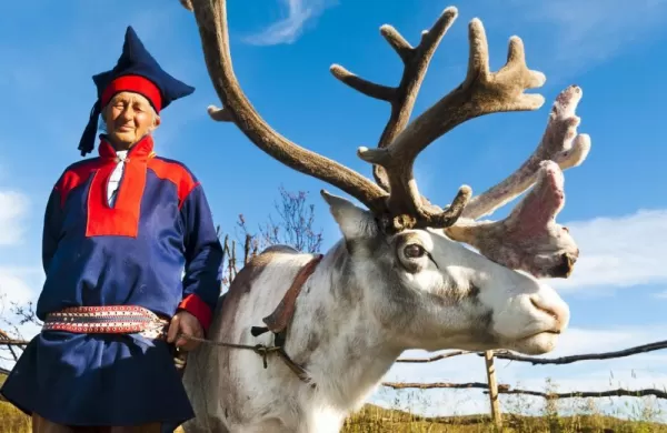 A local man in traditional norwegian dress and his reindeer