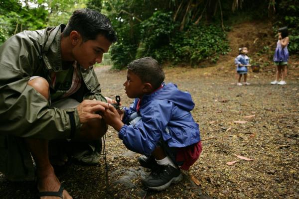 A guide shows a young boy how to use a compass in the rainforests of Belize