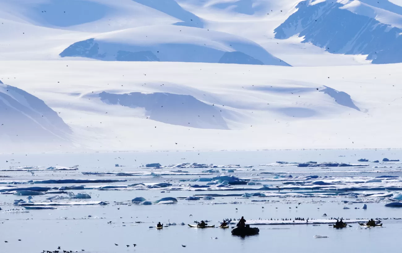 Kayakers and zodiacs cruise the waters of the Arctic