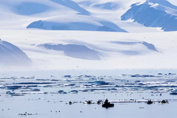 Kayakers and zodiacs cruise the waters of the Arctic